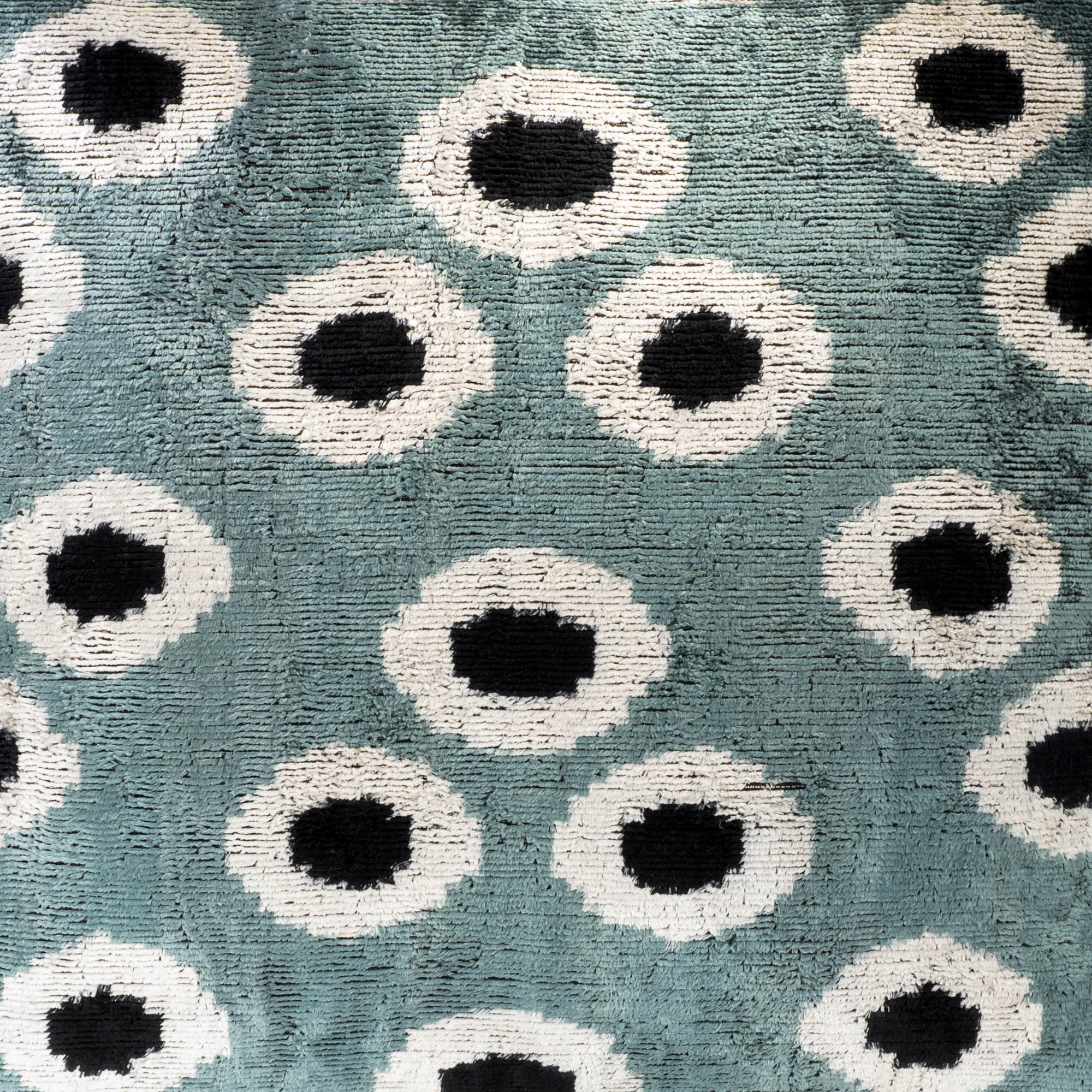 Detailed view of aqua green and white orb ikat pattern on silk velvet pillow cover, highlighting artisan textile design and rich texture.