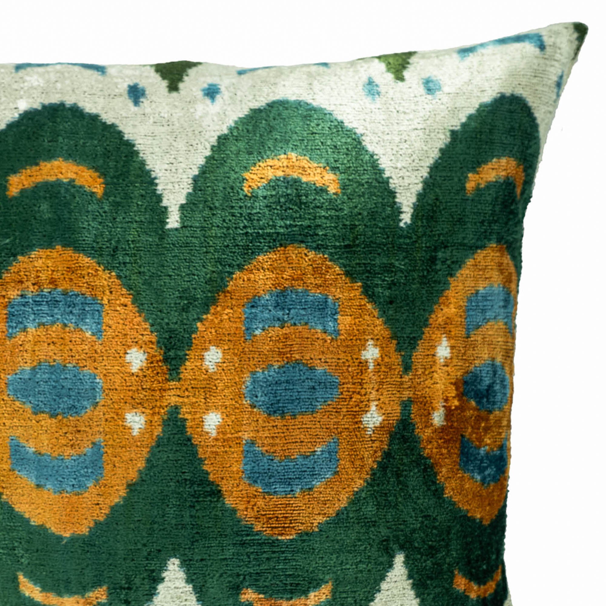 Close-up detail of Mamba silk velvet ikat pillow cover showcasing its green, orange and blue geometric design and luxurious velvet texture.