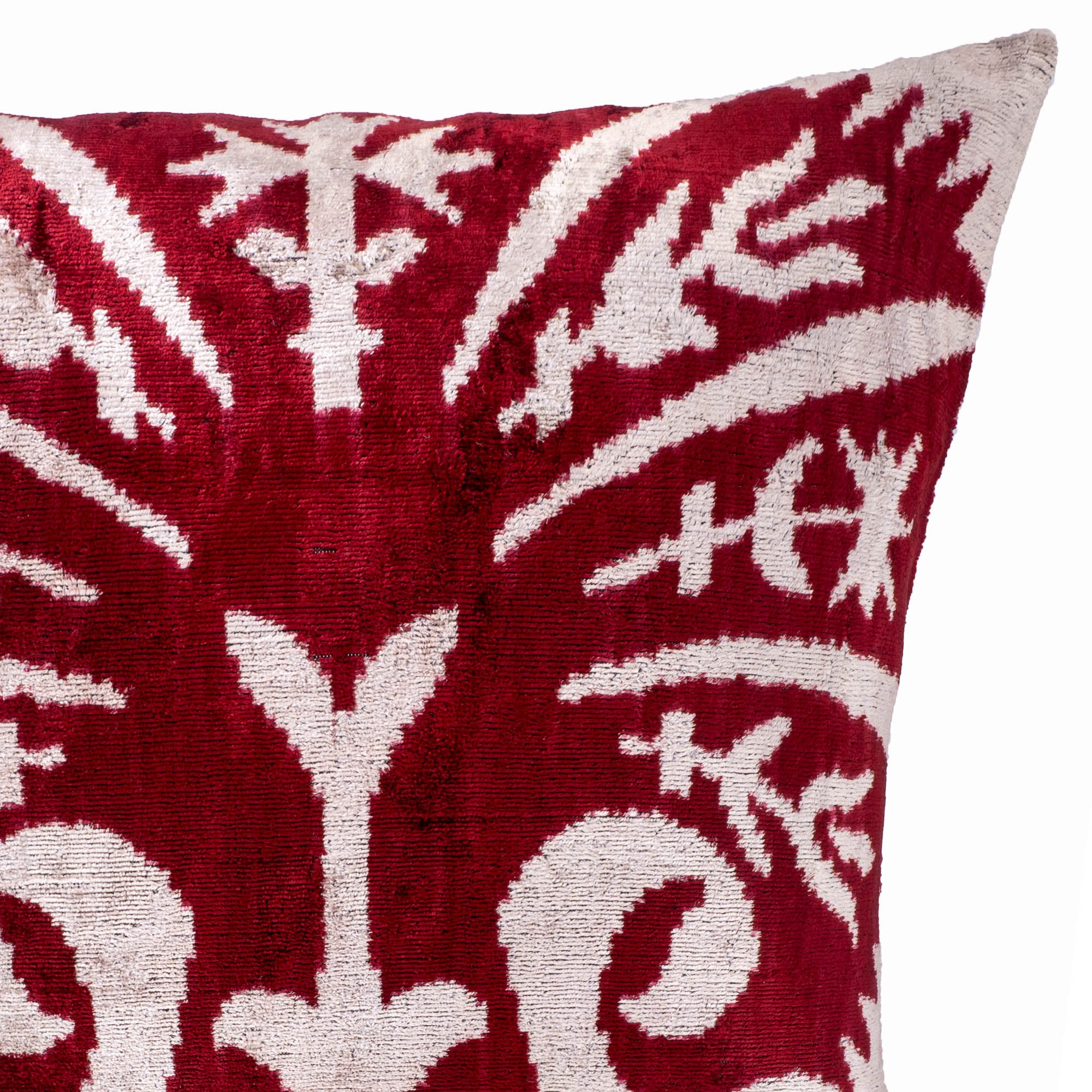 Elegant silk velvet pillow showcasing bold Peacock-inspired Ikat patterns in red and white.