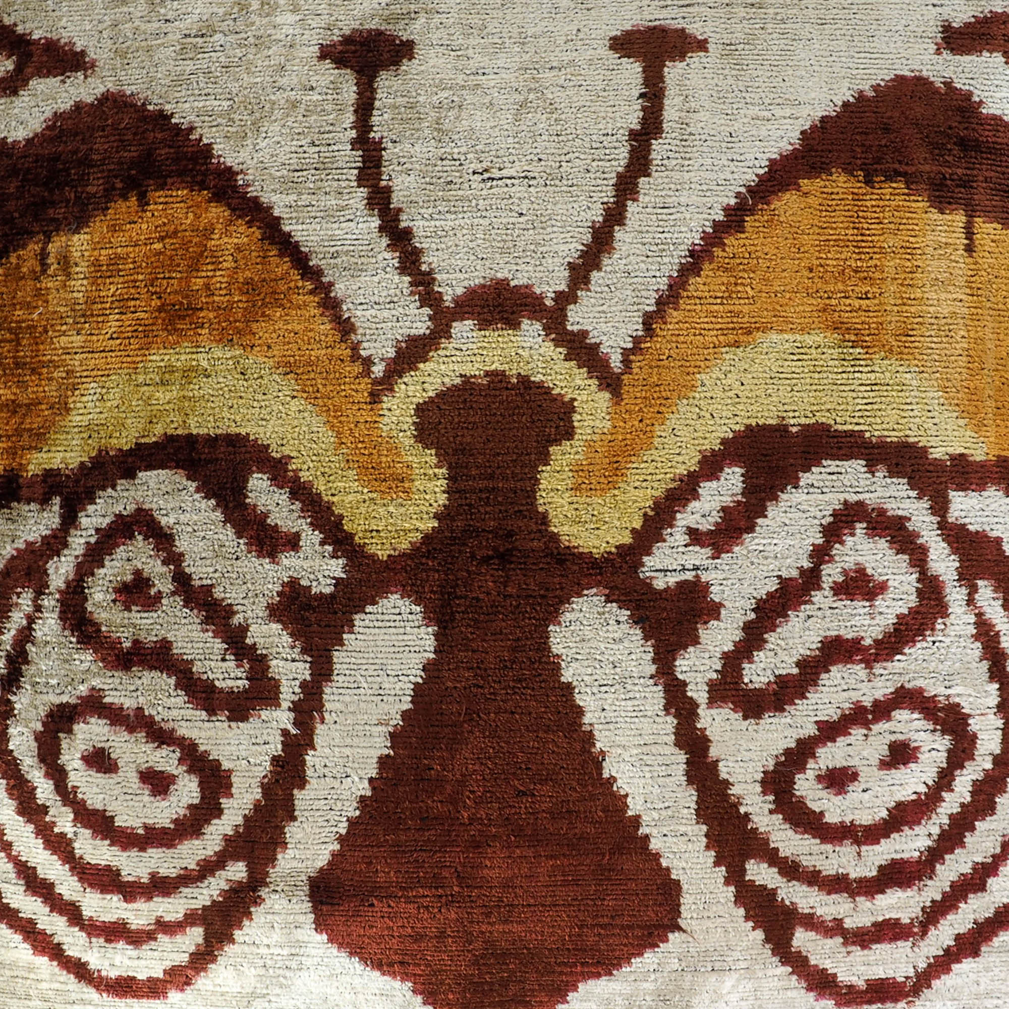 Artisan silk velvet pillow with abstract butterfly pattern in rich ochre, rust, and ivory tones.