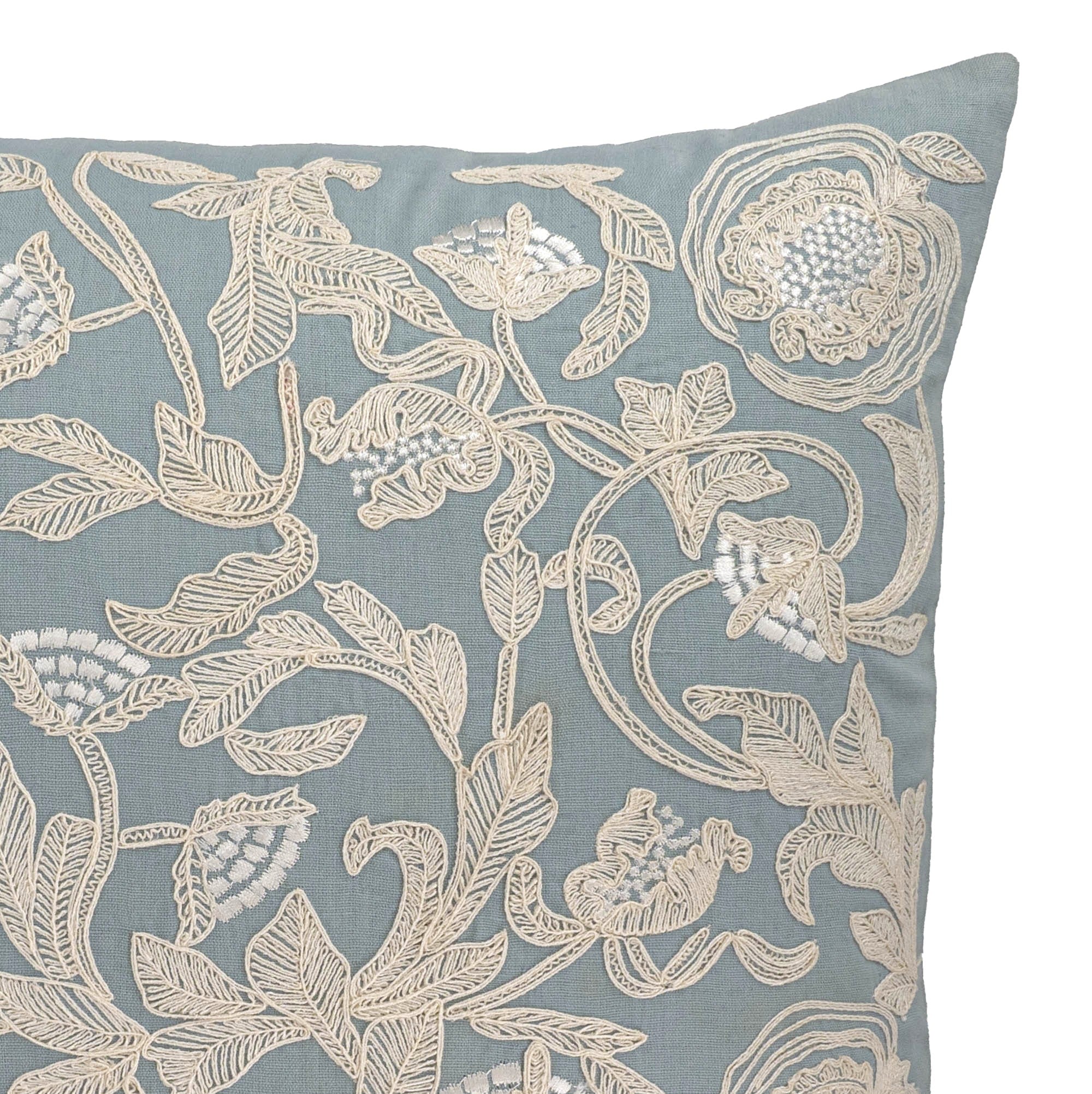 Elegant square throw pillow with intricate ivory floral embroidery on soft blue linen.
