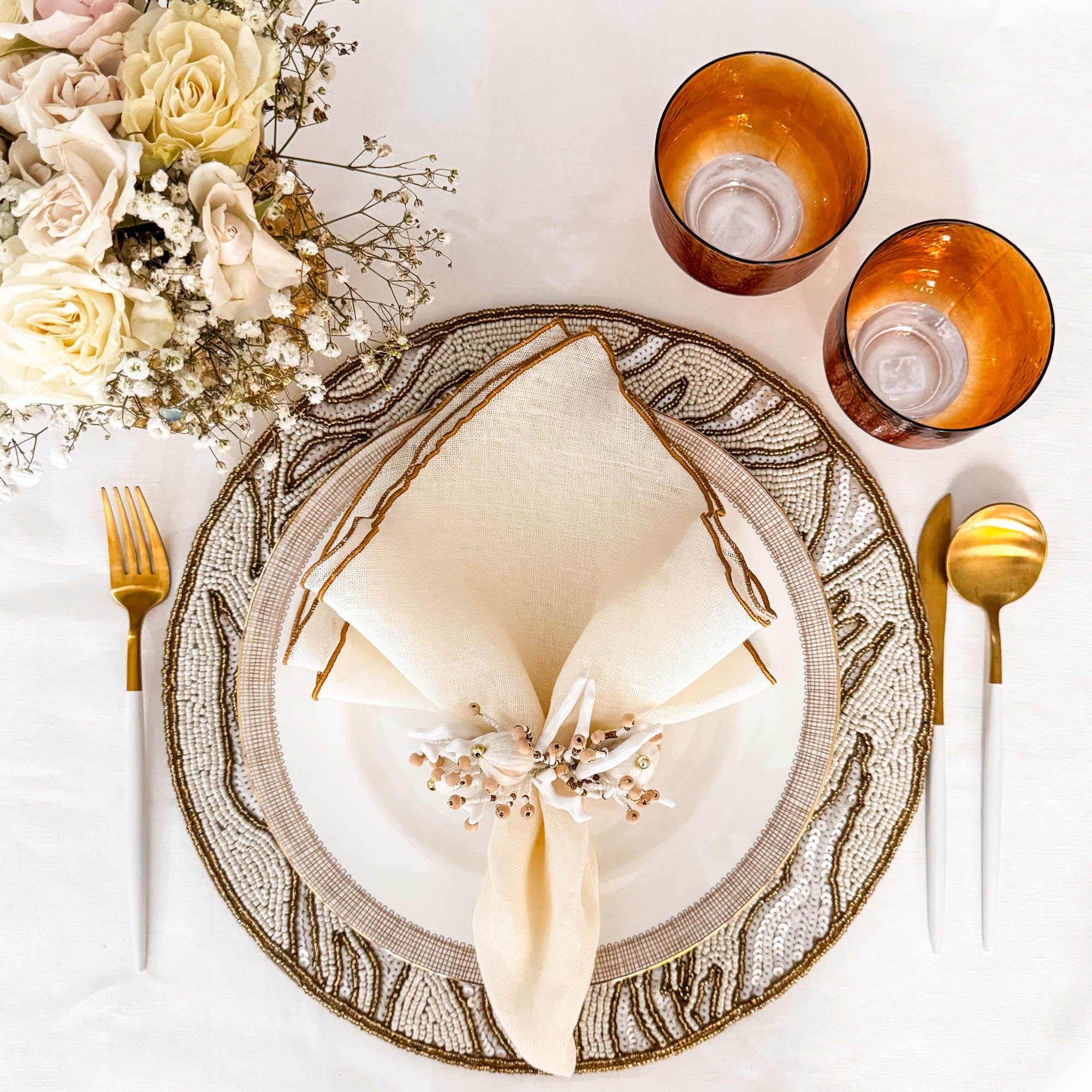 Handcrafted gold and ivory glass beaded placemat styled with floral arrangement and white table linen by ChouChou Touch