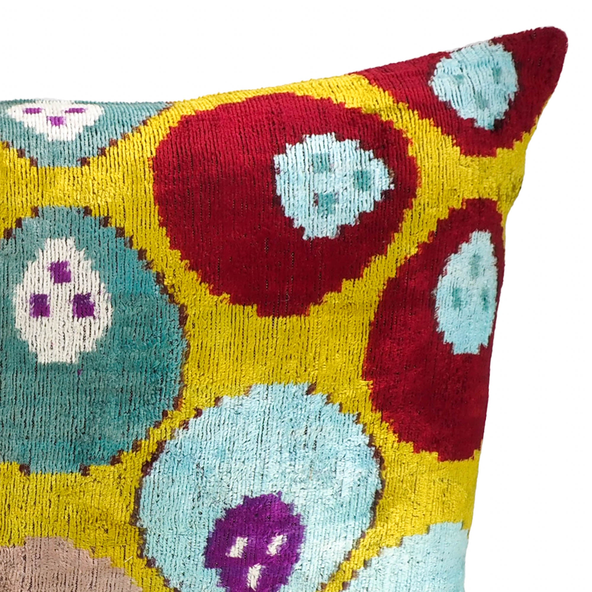 Handwoven ikat pillow cover in rich yellow, purple, red, and aqua tones with fruit-inspired design.