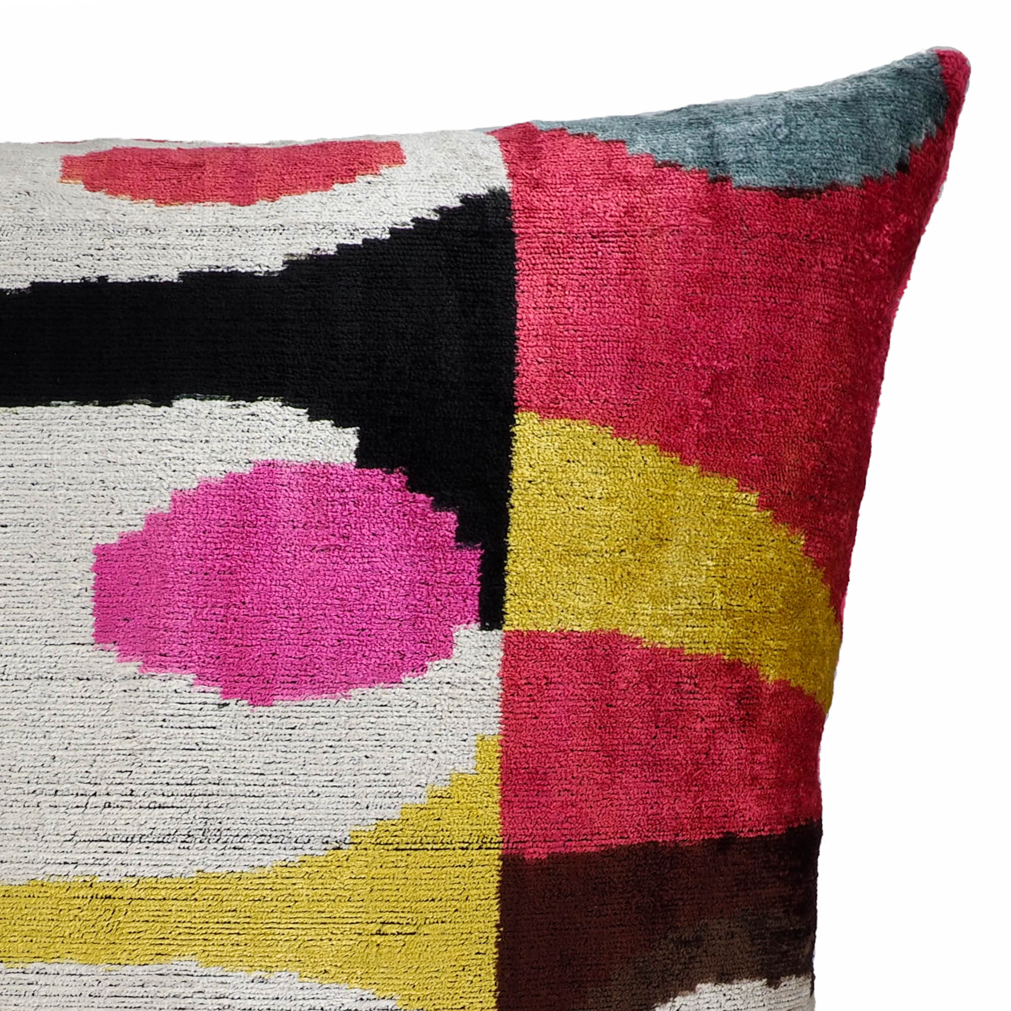 Square silk velvet cushion with vivid ikat pattern in hot pink, gold, and deep red sections.