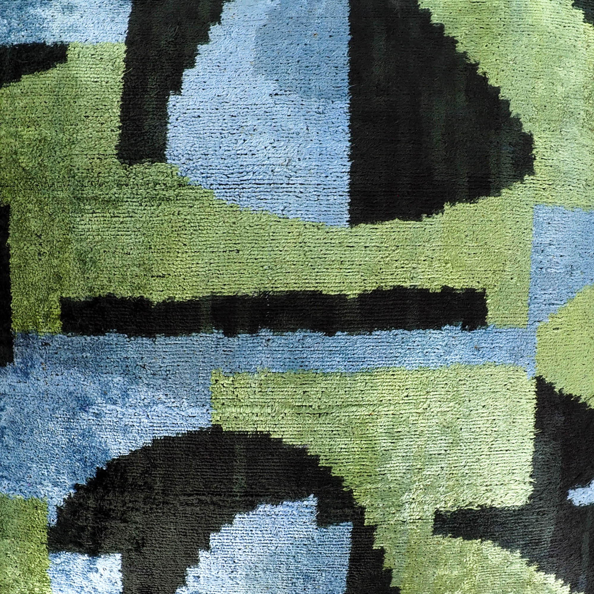 Silk velvet cushion cover with rich green and blue abstract print on a soft, shimmering surface.