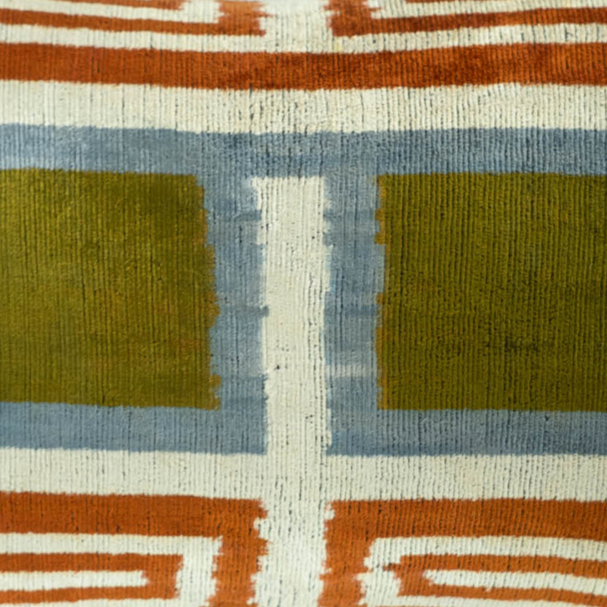 Geometric-patterned throw pillow in silk velvet, featuring a contemporary Ikat design with green, orange, and blue accents.