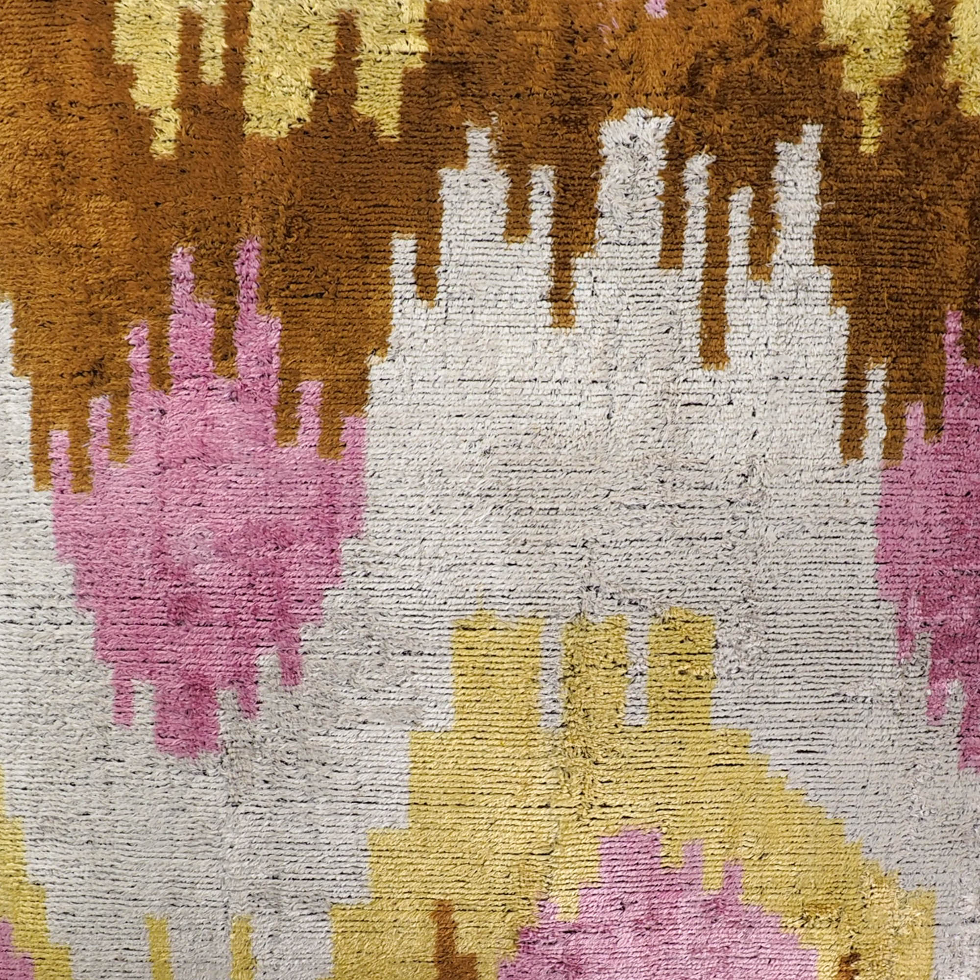 Handwoven silk pillow cover with abstract pink and mustard ikat motif on a neutral base.