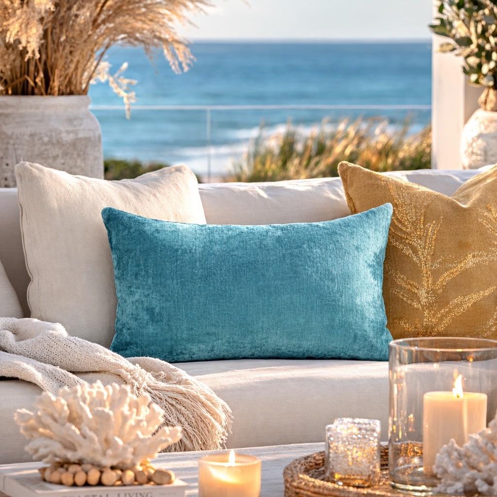 Turquoise silk velvet ikat lumbar pillow cover 16x24 styled on a beige sofa in a coastal living room with ocean view