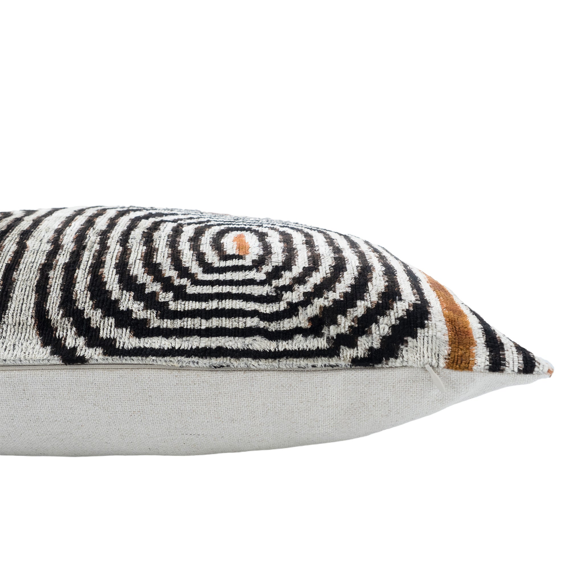 Side view of a handwoven silk velvet ikat lumbar pillow cover featuring a hidden zipper closure, black, ivory and bronze geometric pattern, and a solid ivory silk velvet backing against a clean white studio background.