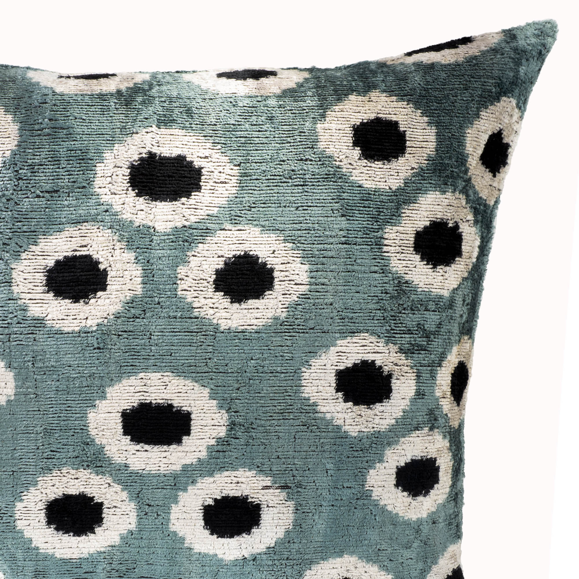 Close-up detail of aqua green silk velvet ikat fabric featuring white orb motif, showcasing texture, craftsmanship and luxurious velvet weave.
