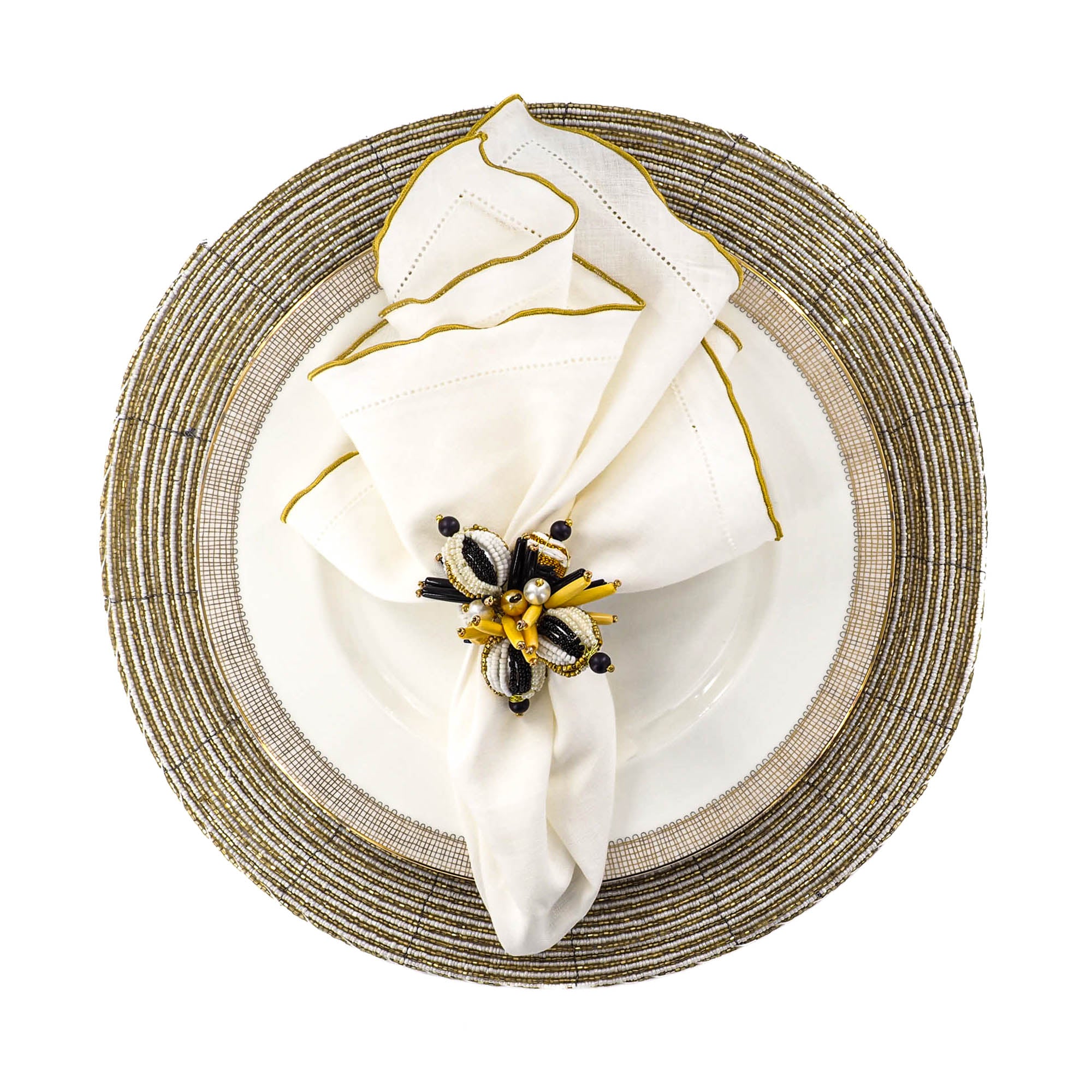 Decorative table setting with a white napkin, gold napkin ring, and black and gold brooch on a white background.
