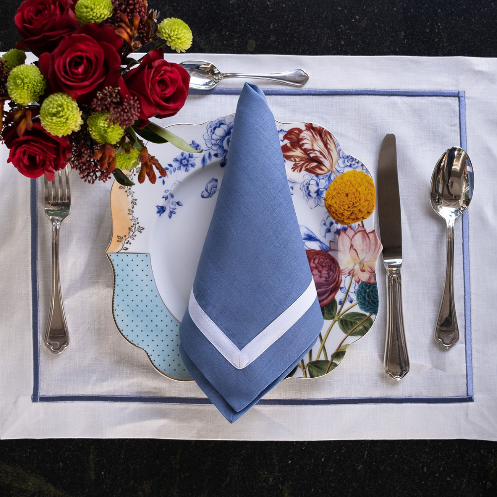 Blue linen napkin with white border on elegant table setting with white placemat, floral dinner plate and luxury dining decor