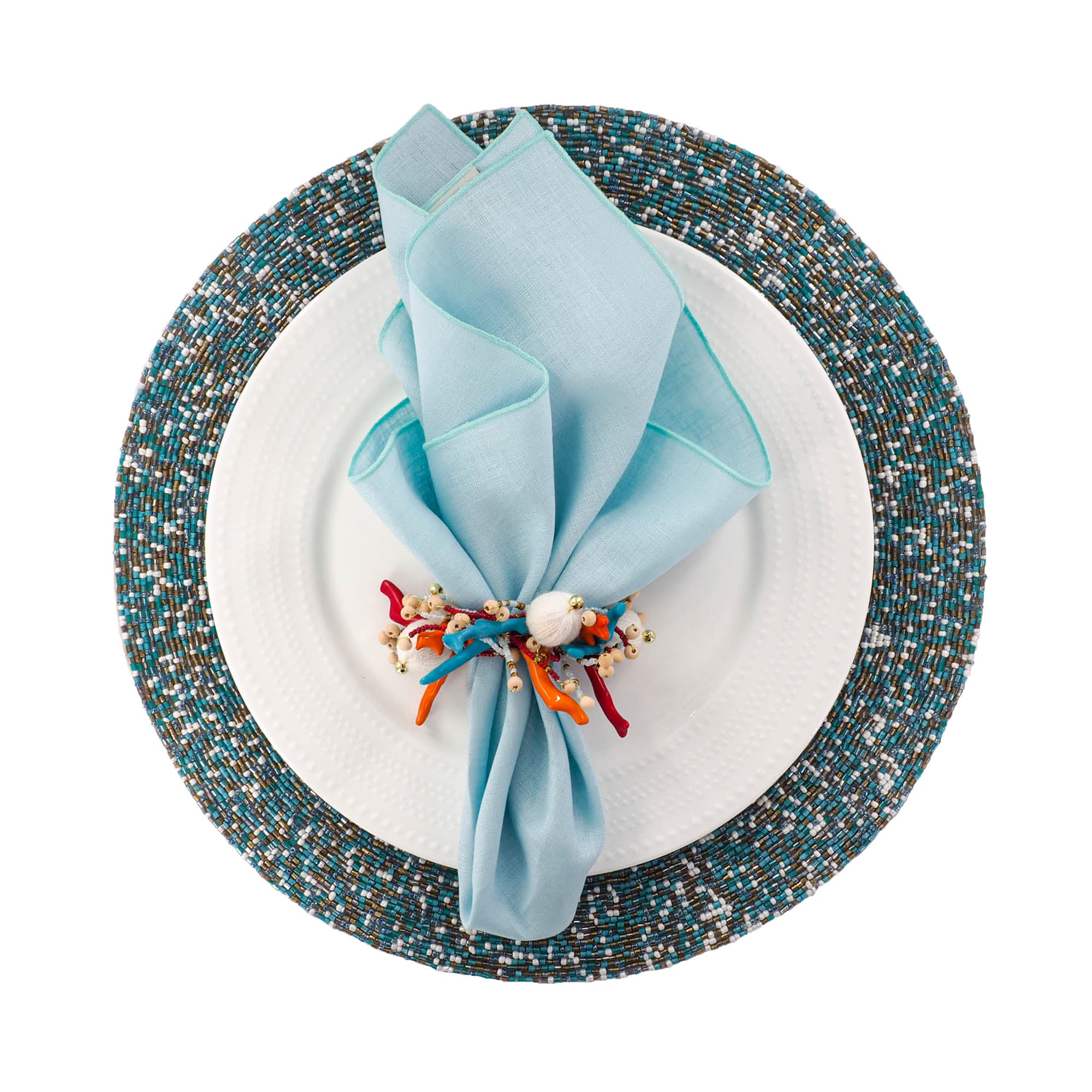Napkin folded on a white plate with decorative napkin ring, placed on a round beaded multicolor placemat.