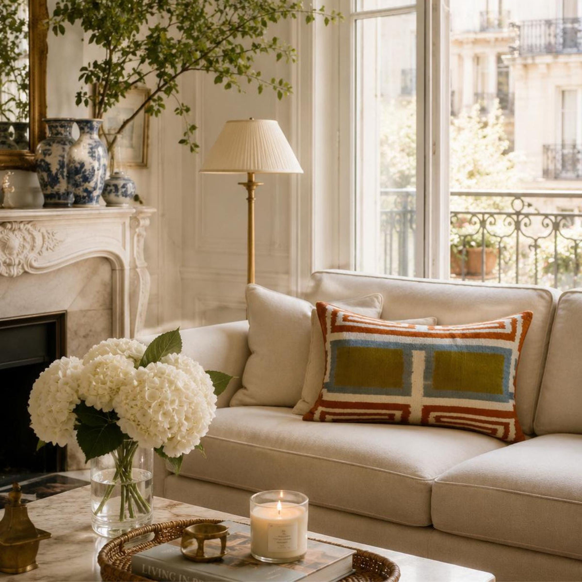 Soho Light silk velvet ikat lumbar pillow styled on a neutral sofa in an elegant living room, featuring olive green, soft blue, and rust geometric patterns.