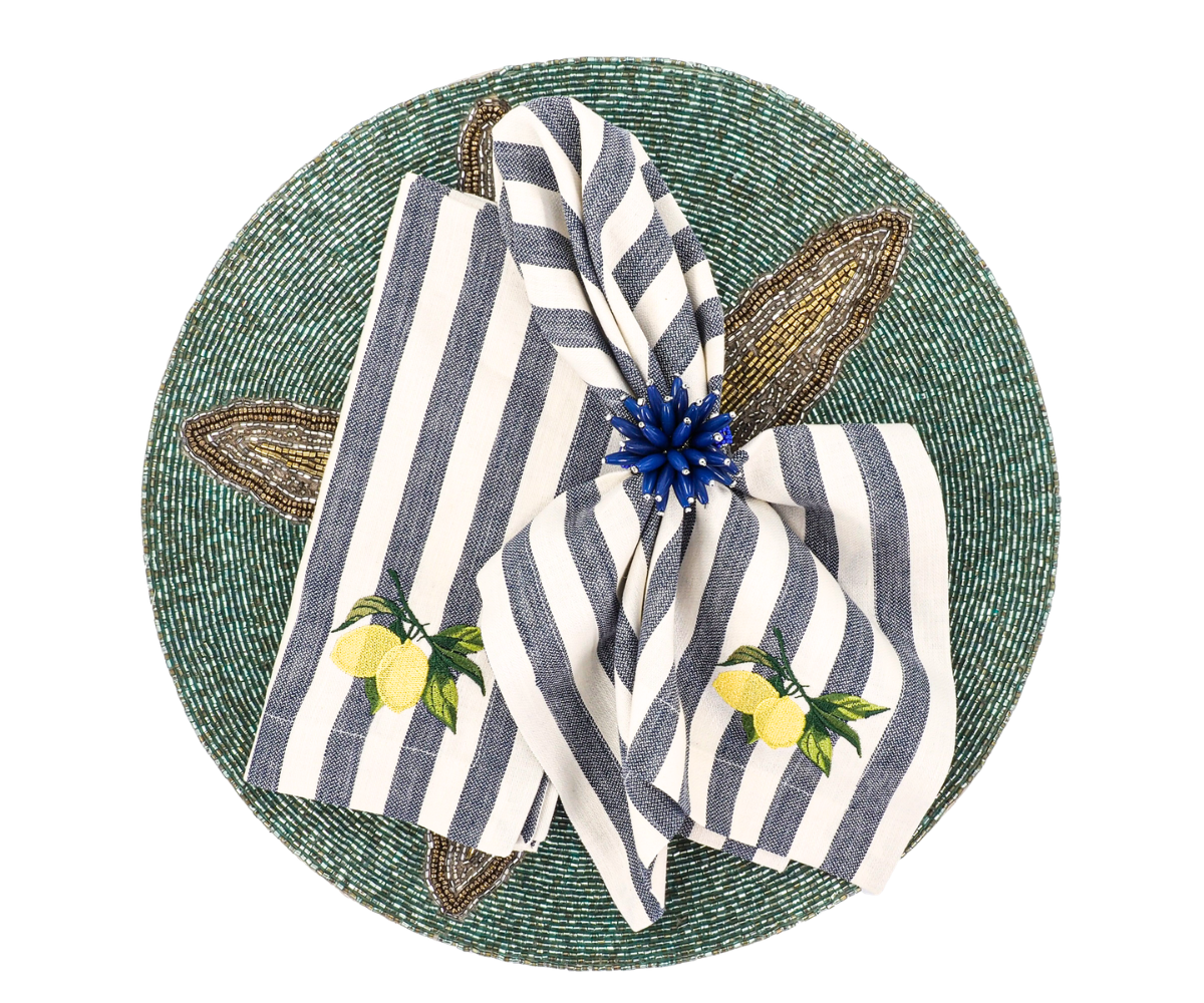 Blue and white striped linen napkins with yellow lemon embroidery styled on a green beaded placemat