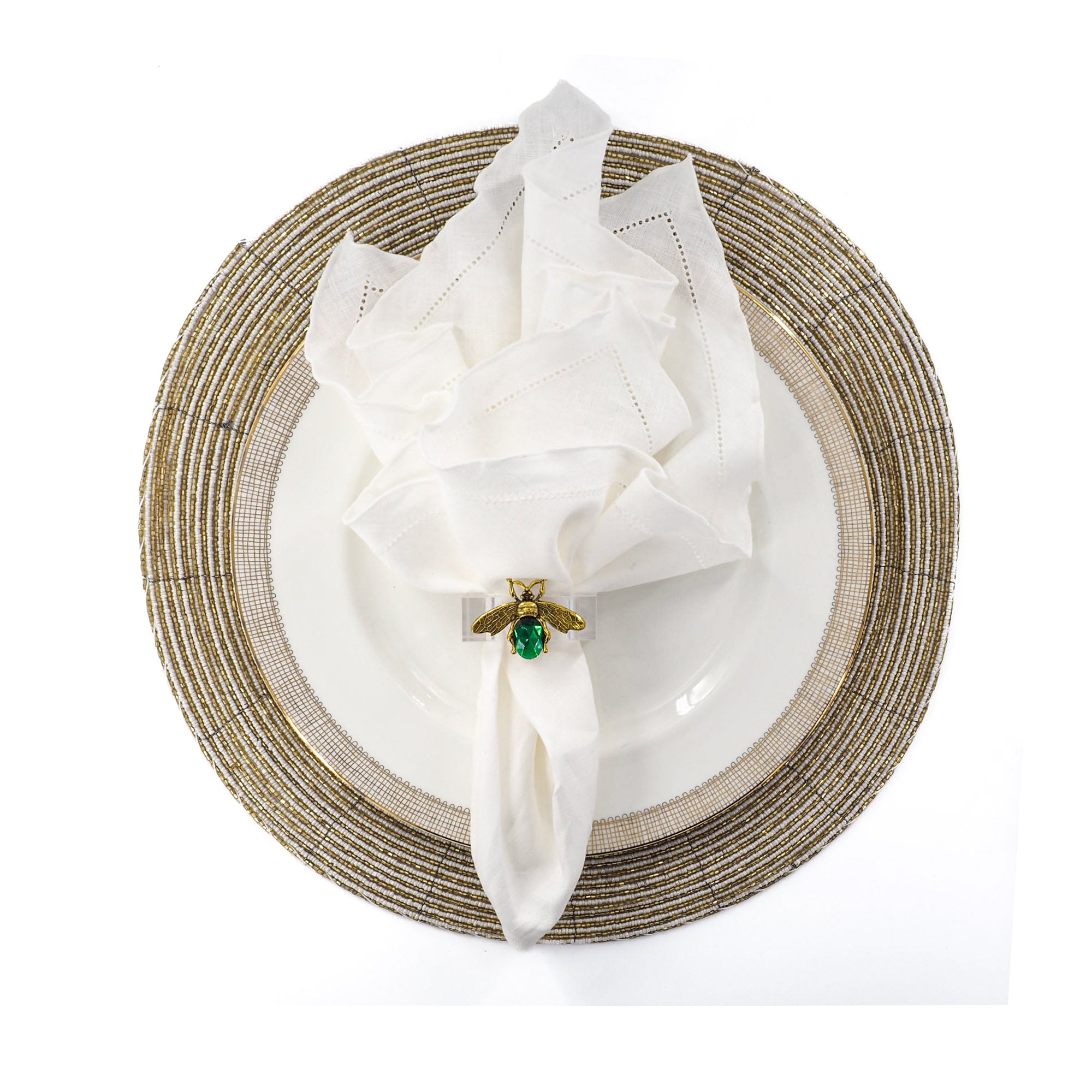 White linen napkin with ruffle hemstitched edges, elegantly folded on a white and gold dinner plate with matching gold beaded placemat.