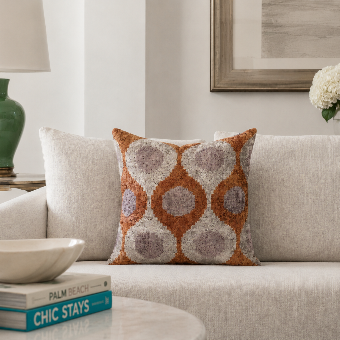 Luxury orange silk velvet ikat throw pillow beautifully styled on a cream sofa in a bright Palm Beach-inspired interior.