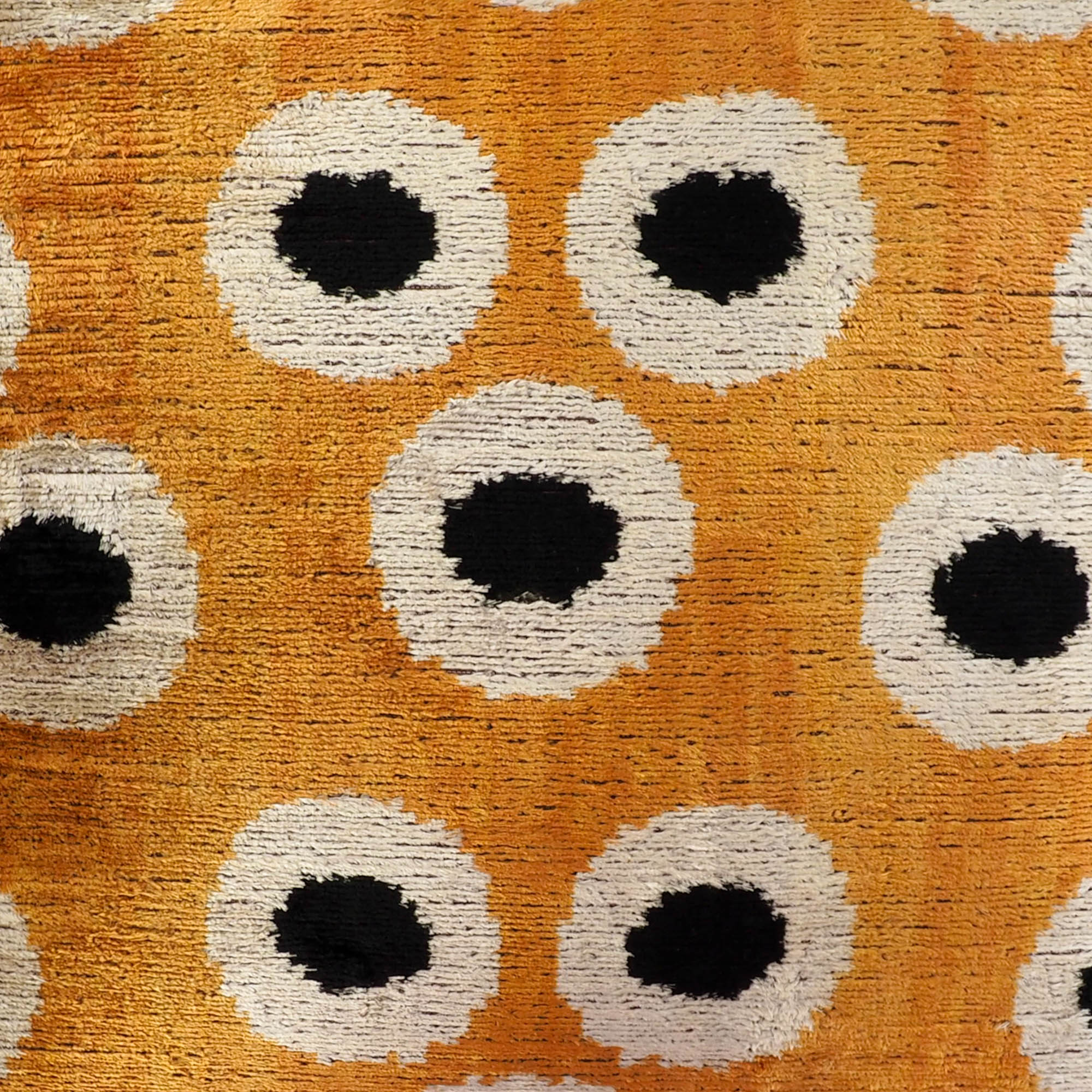 Detailed close-up of the Orange Orbs Silk Velvet Ikat Throw Pillow, 20 x 20, featuring luxurious handwoven Ikat patterns with vibrant orange orbs on a smooth velvet fabric.