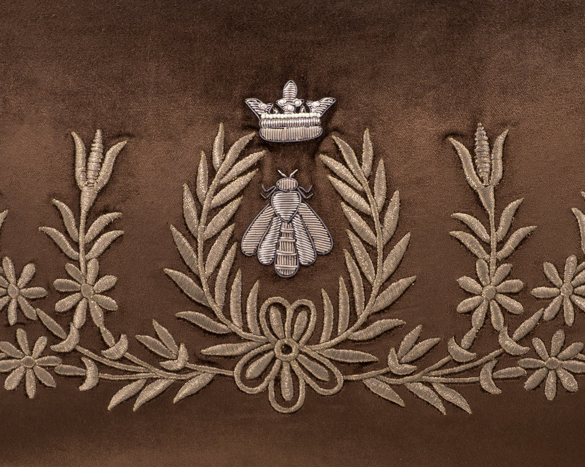 Close-up of the crowned bee motif on Regina brown silk velvet, framed by embroidered leafy branches and flowers.