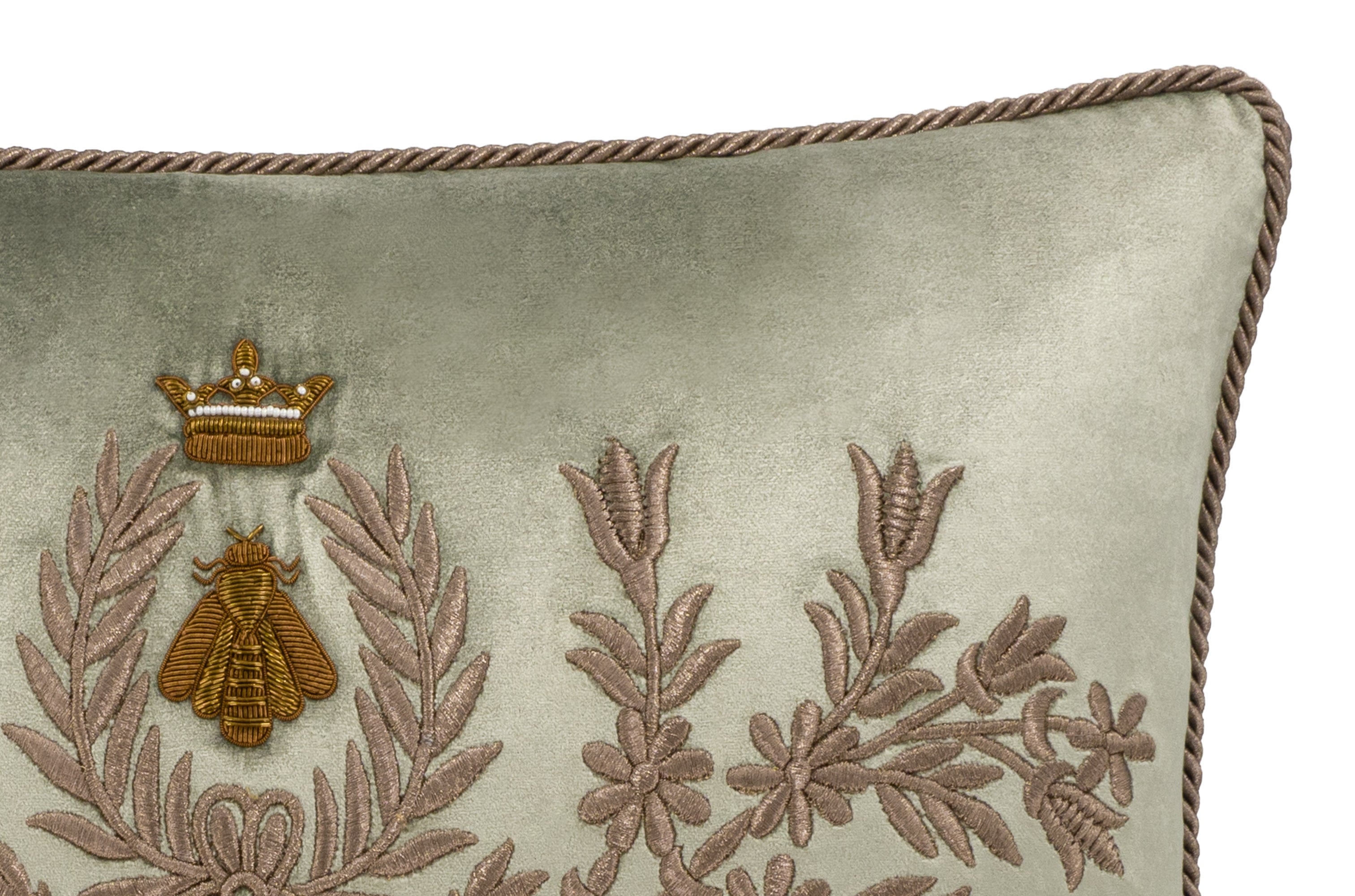 close up of embroidered crown and bee motif with floral detailing on sage green silk velvet pillow, showcasing intricate craftsmanship and rich texture on a clean background