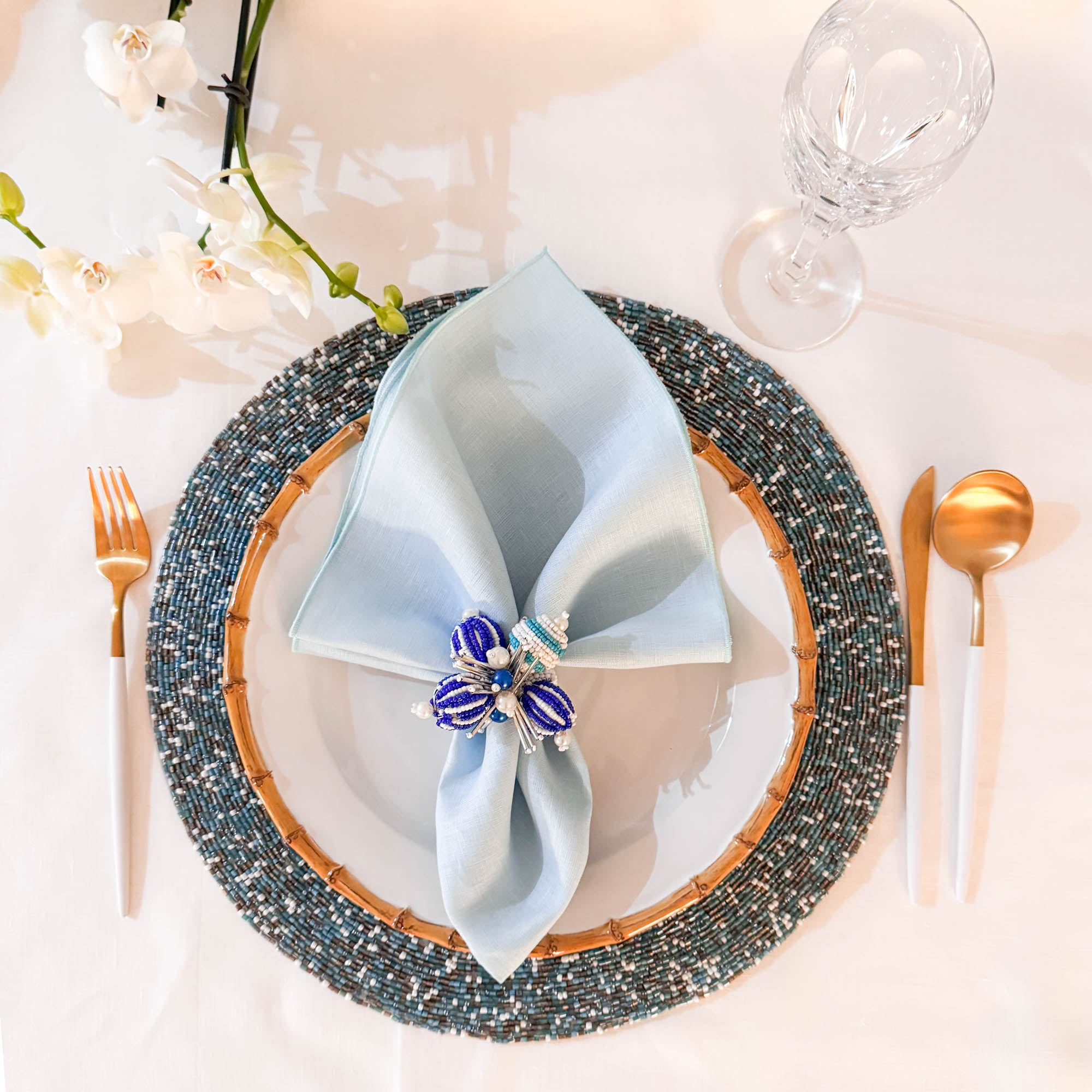 Round seaside glass beaded placemat with coastal blue, gold , copper and silver tones on a white background by ChouChou Touch