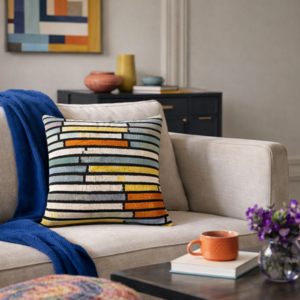 modern striped silk velvet ikat decorative throw pillow cover with yellow blue and orange accents styled on a beige sofa in a bright contemporary living room
